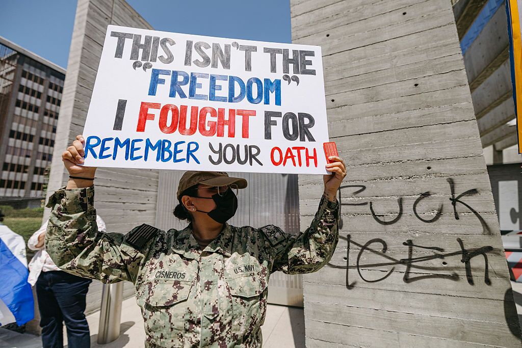 A woman holds a sign that reads "This isn't the freedom I fought for"